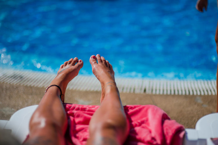 Low section of woman resting on swimming pool