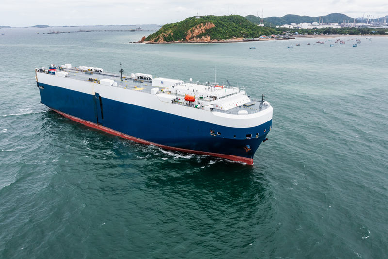 Roll-on roll-of ship loading new cars line up . automotive container carriers floating in sea,