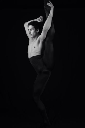 Shirtless man dancing against black background