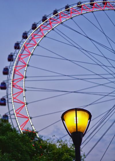 Low angle view of illuminated street lamp against ferris wheel at dusk
