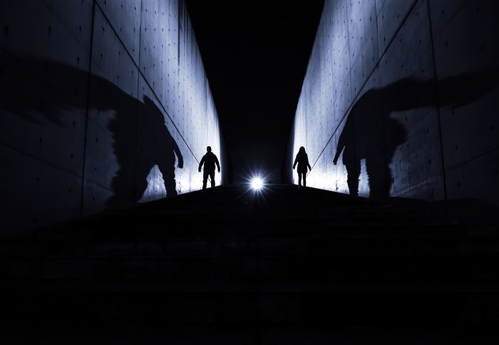 Low angle view of silhouette people on footpath amidst walls at night