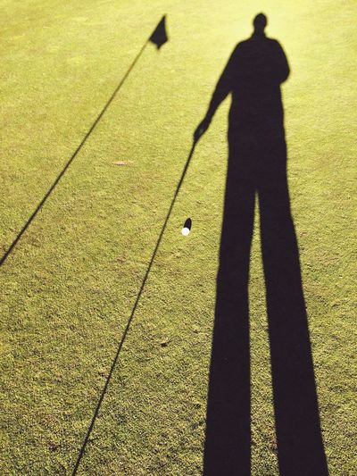 High angle view of golfer shadow on green course