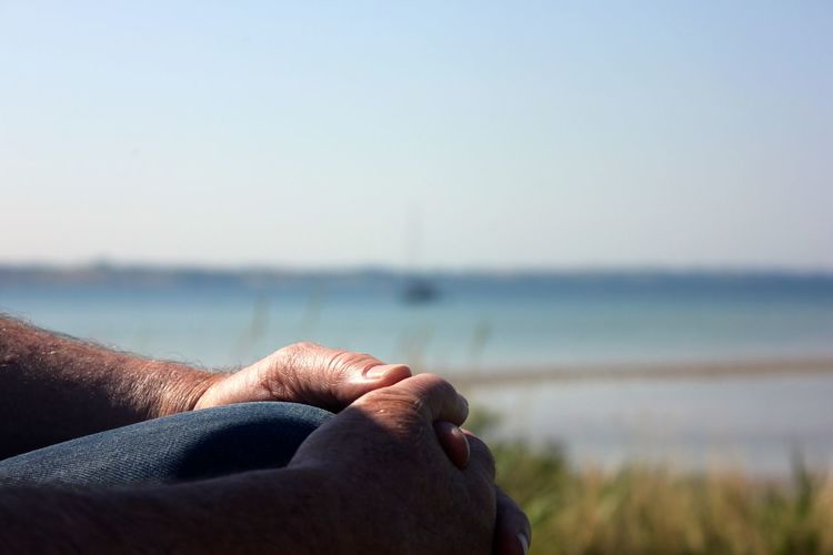 Close-up of person sitting outdoors against sky