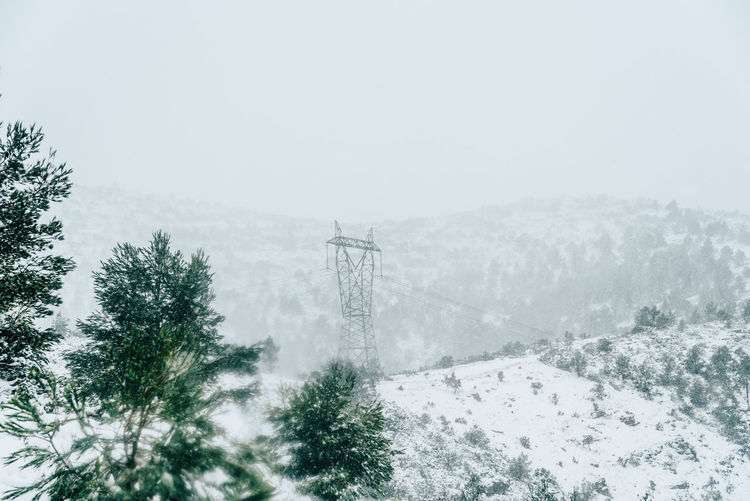 Electricity pylon on snow covered landscape