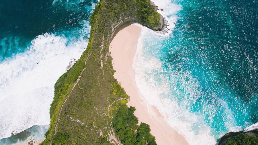 Kelingking sandy beach with tall overgrown rocky cliff and turquoise ocean on  nusa penida island