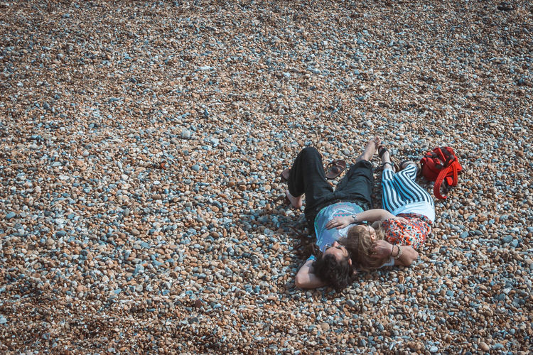 High angle view of couple relaxing on pebbles at beach