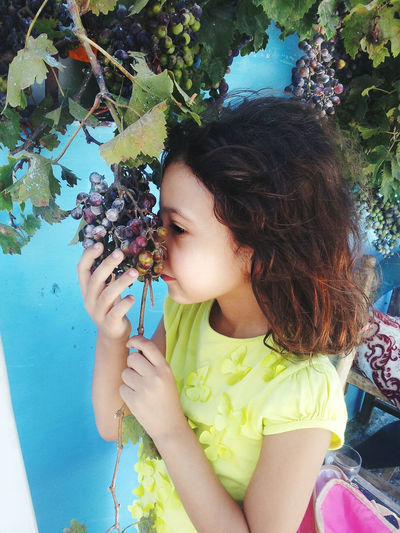 Close-up of girl holding apple against tree