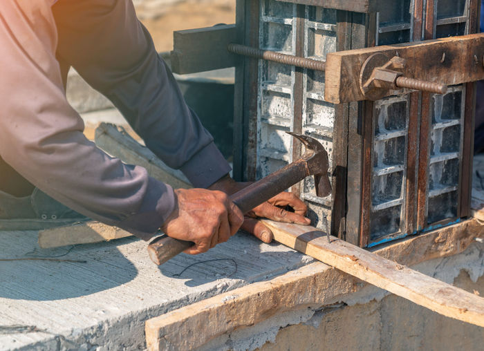 Workers drive concrete nails into wooden bars along the edge of the floor to support the posts.