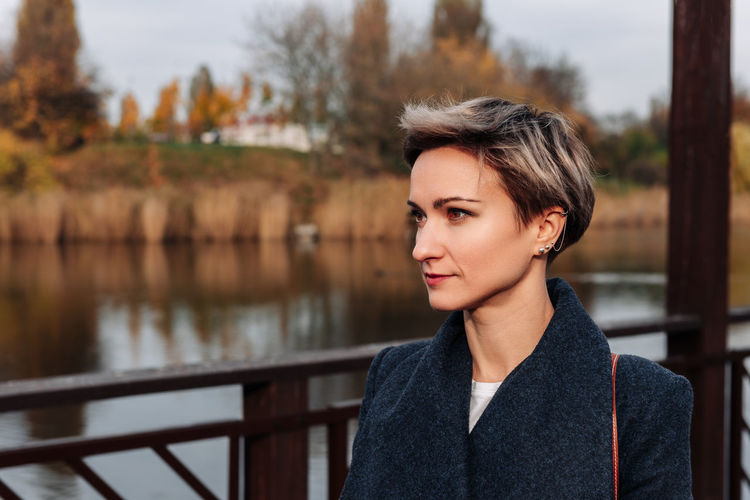Woman look away against the backdrop of the river in autumn
