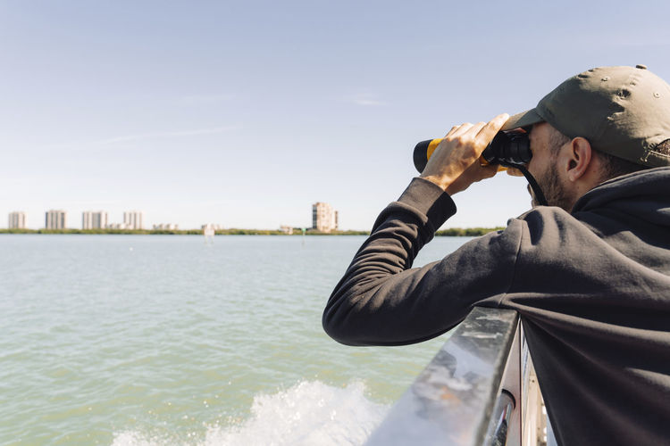 Usa, florida, sanibel, man looking at sea through binoculars