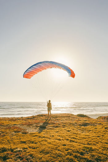 Young man paragliding during sunset over cliffs in baja, mexico.