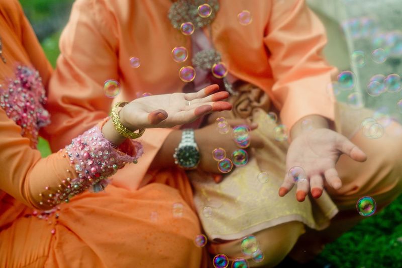 Midsection of couple in traditional clothing playing with bubbles