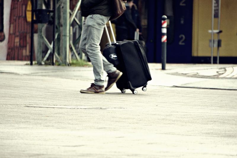 Low section of man walking with luggage in city