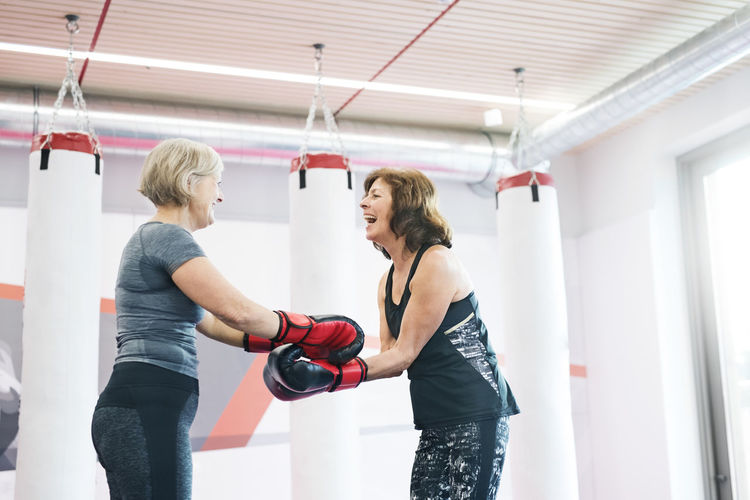 Two happy senior women with boxing gloves in gym