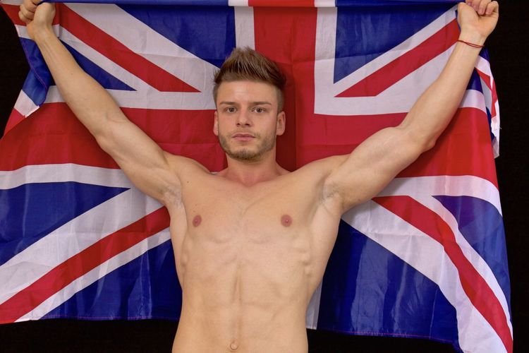 Portrait of shirtless muscular man with australian flag standing against black background