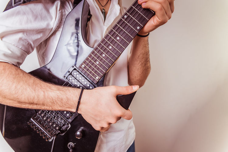 Midsection of man holding guitar
