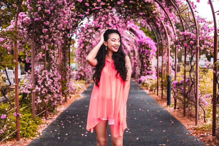 Portrait of beautiful young woman standing by pink flower