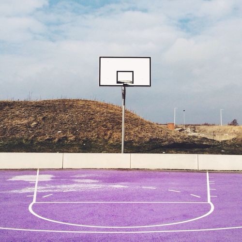 Empty basketball court against landscape and clouds