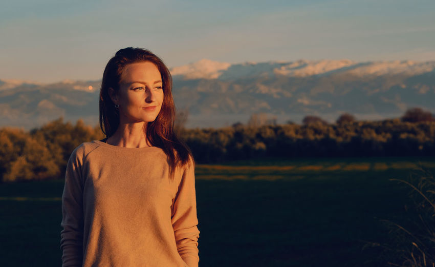 Young woman standing against sky