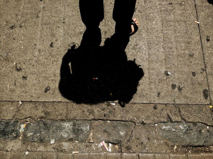 Low section of man with shadow on street