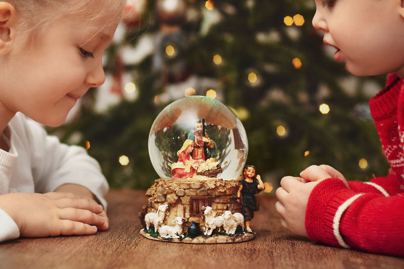 Children looking at a glass ball with a scene of the birth of jesus christ