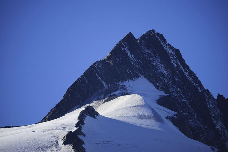 Scenic view of snowcapped mountain against clear blue sky during winter