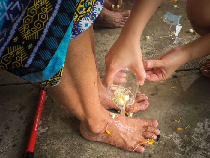 High angle view of woman washing feet with jasmine water during songkran festival