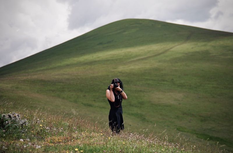 Full length of woman photographing on field