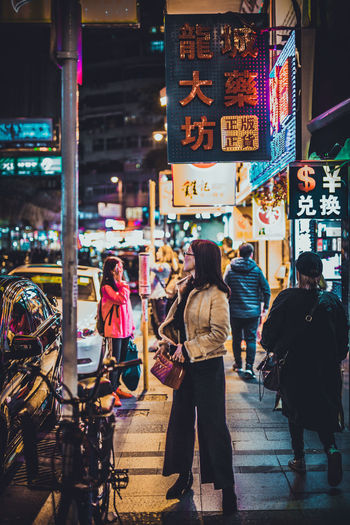 Rear view of people walking on illuminated street