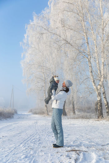 Full length of mother standing with daughter on snow covered land