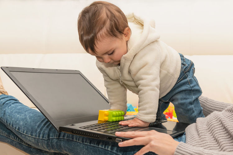 Cute baby playing with mothers laptop