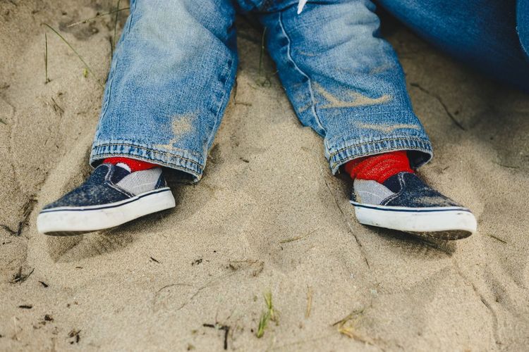 Low section of child sitting on sand at playground