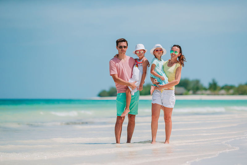Full length of cheerful family standing on beach