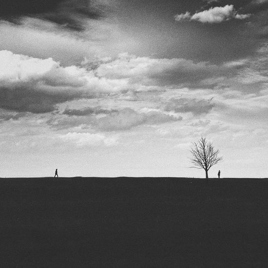 Silhouette of man on landscape against cloudy sky
