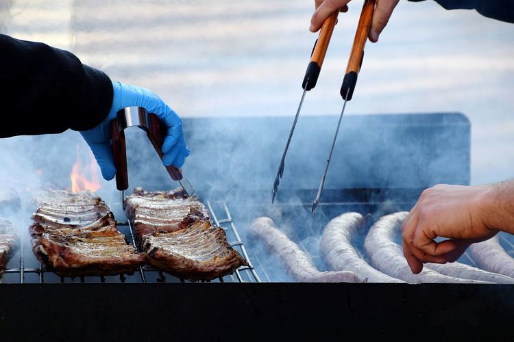 Close-up of men holding food on barbecue grill