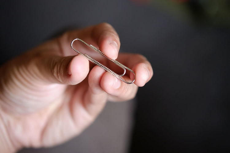 Cropped image of hand holding paper clip