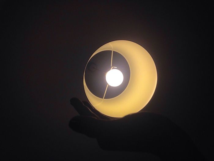 Close-up of illuminated light bulb against sky