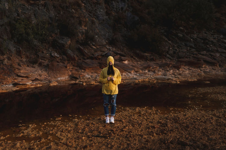 Young lady in yellow raincoat strolling in nature