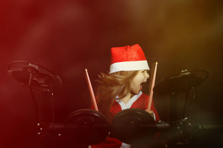 Cheerful girl playing drum at music concert