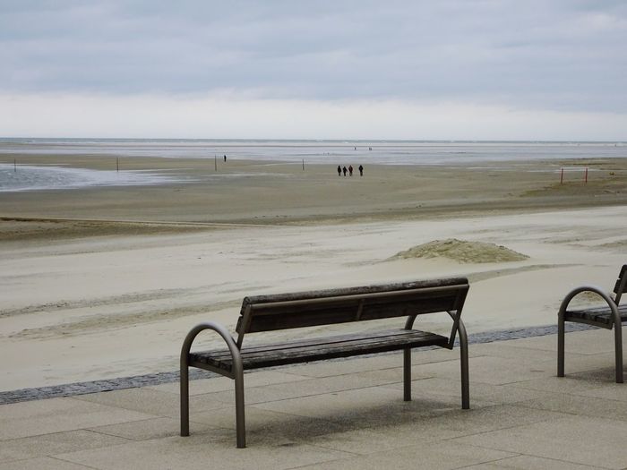 Empty seats on beach against sky