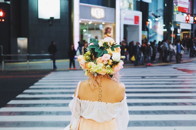 Rear view of a woman with flowers on head crossing road