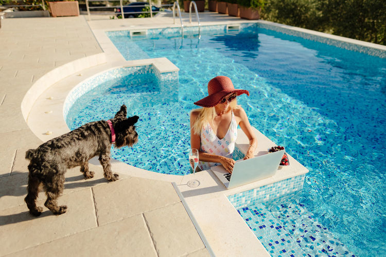 High angle view of woman with dog sitting in swimming pool
