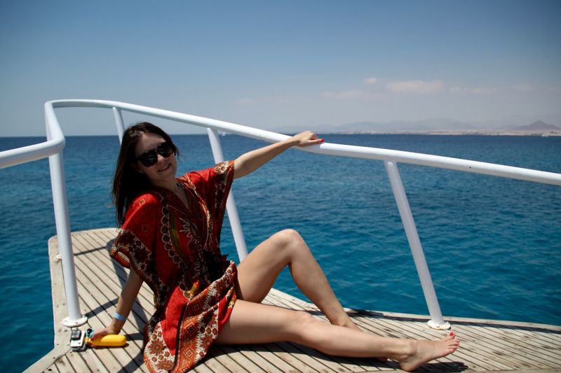 Young woman sitting on boat sailing in sea against sky