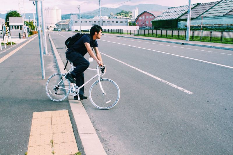 Side view of young man with bicycle on road
