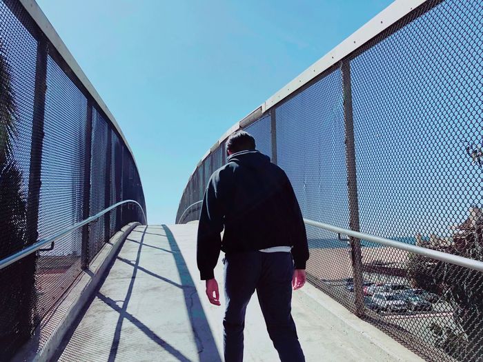 Rear view of man walking on footbridge