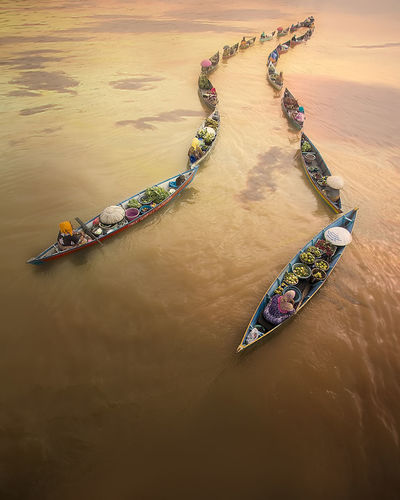 High angle view of people on floating market at river during sunset