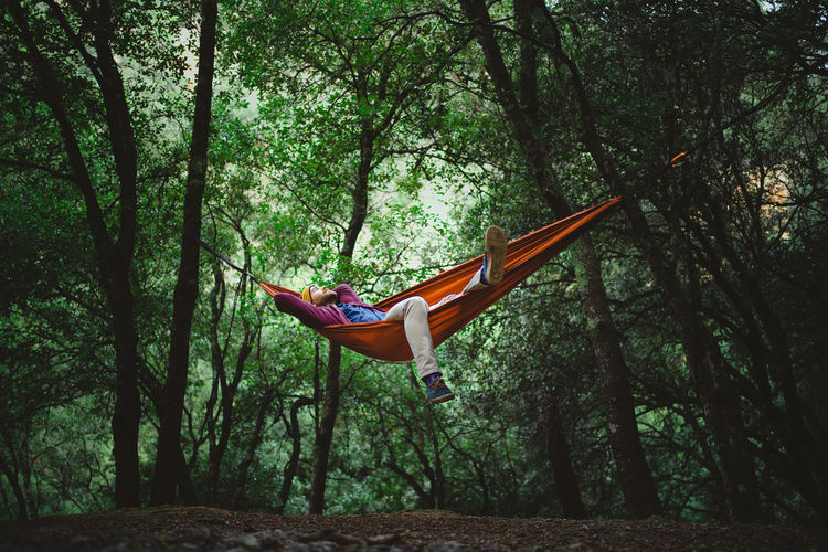 Young male rests on a hammock in the middle of the forest