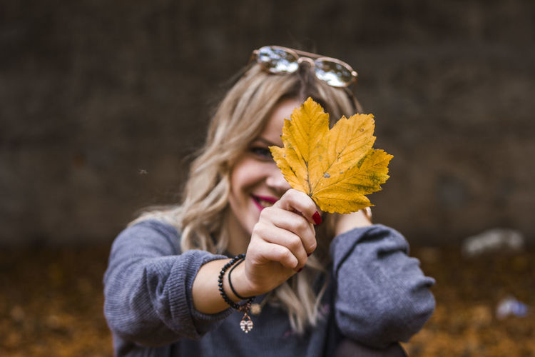 Woman holding yellow leaf during autumn