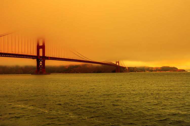 View of suspension bridge over sea during sunset