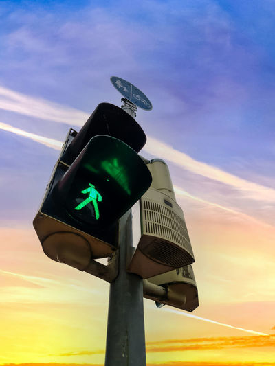 Low angle view of road signal against sky during sunset